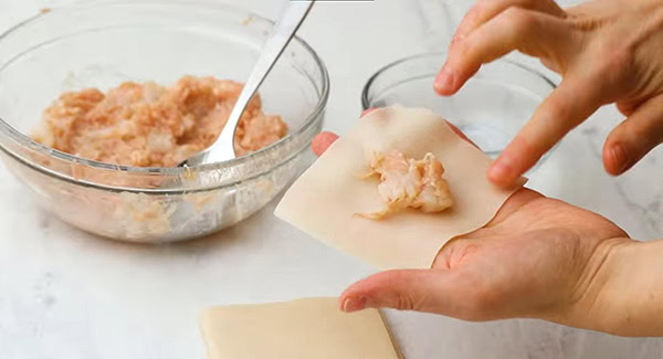 This image shows the filling being place onto the wonton wrapper.