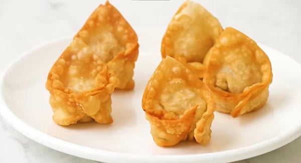 Freshly cooked fried wontons on a plate.