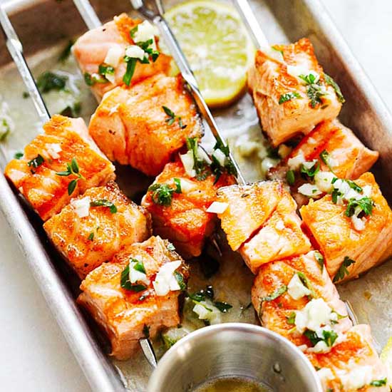 Succulent and juicy garlic butter salmon kebab with a lemon slice on a platter. 