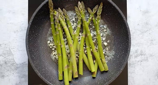Asparagus cooked in garlic and butter in a skillet.
