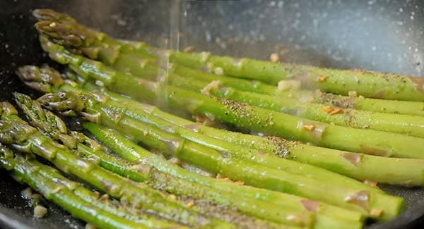 Asparagus being drizzled with lemon juice.