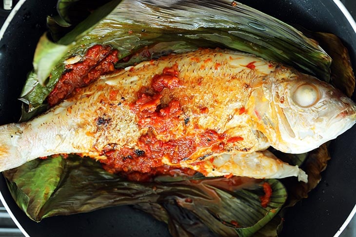 This image shows more sambal being added to the other side of the fish.