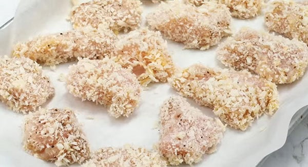 This image shows the breaded Chicken pieces on a baking sheet.