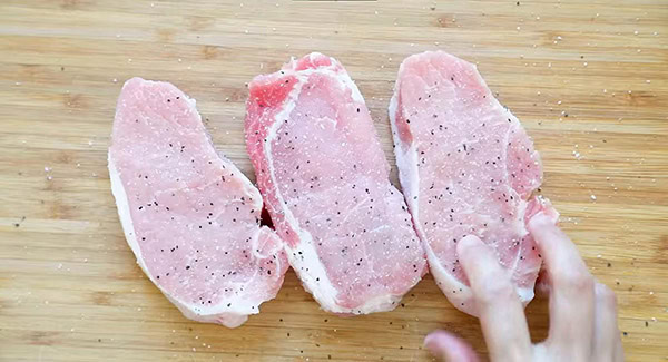 This image shows the Pork Chops being seasoned. 