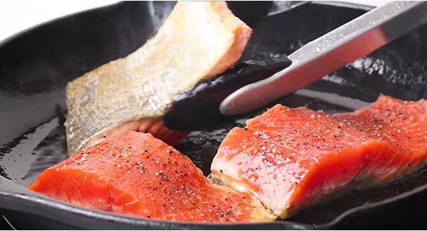 Seasoned salmon fillet on a cast-iron skillet.