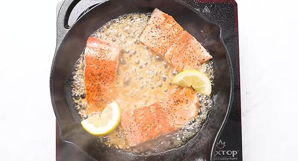 Salmon with lemon slices being broiled in honey mixture. 