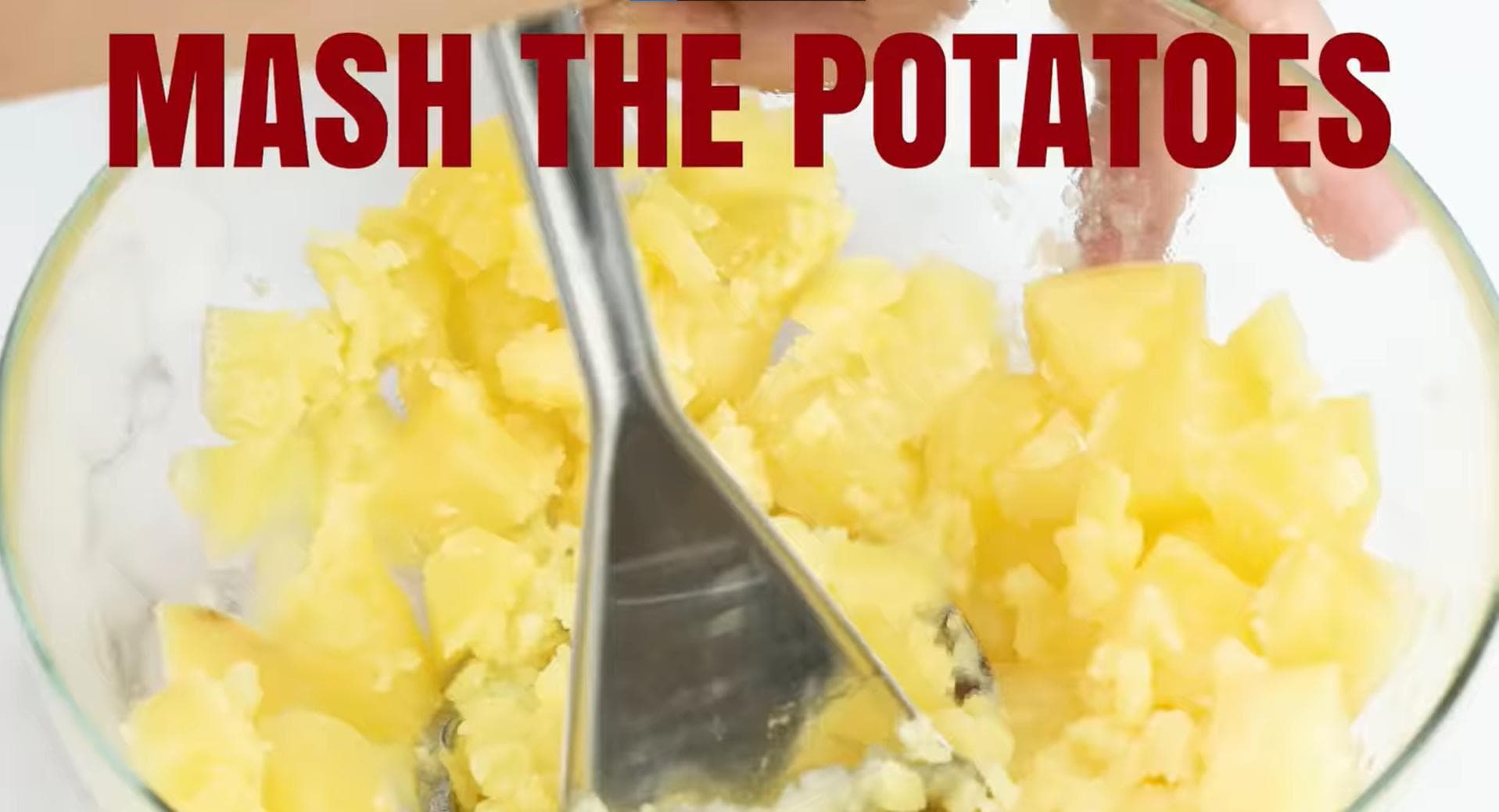 Potatoes being mashed in a bowl. 