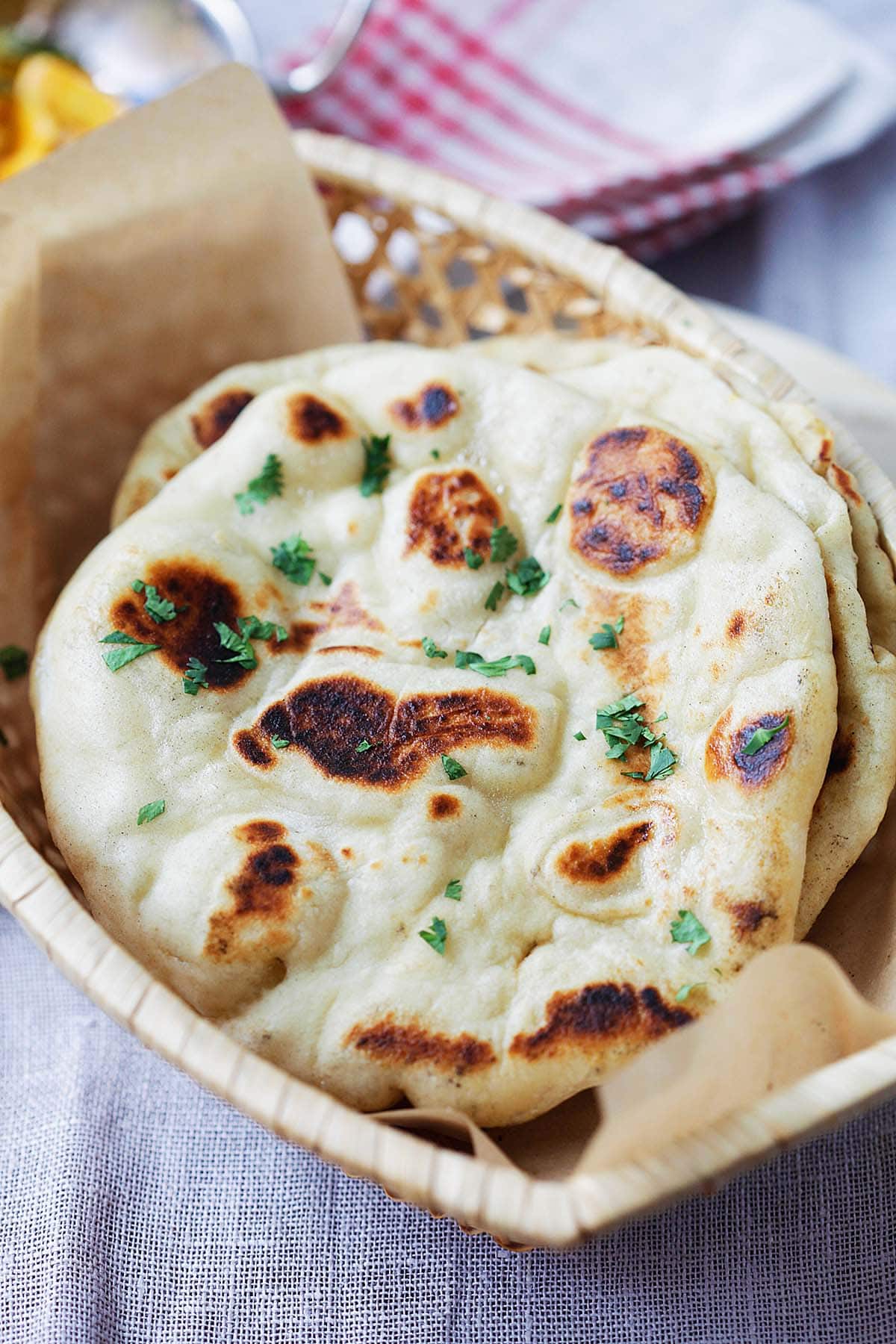 Fluffy and chewy naan with brown bubbly blisters in a bread basket. 