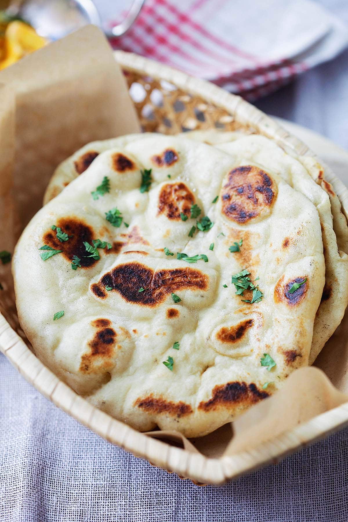 Fluffy and chewy naan with brown bubbles in a bread basket.