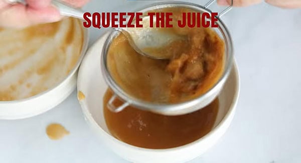 Tamarind pulps in strainer and tamarind juice in a bowl. 