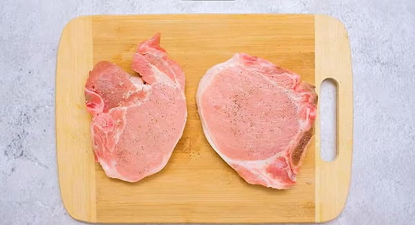 This image shows the Pork Chops being seasoned.