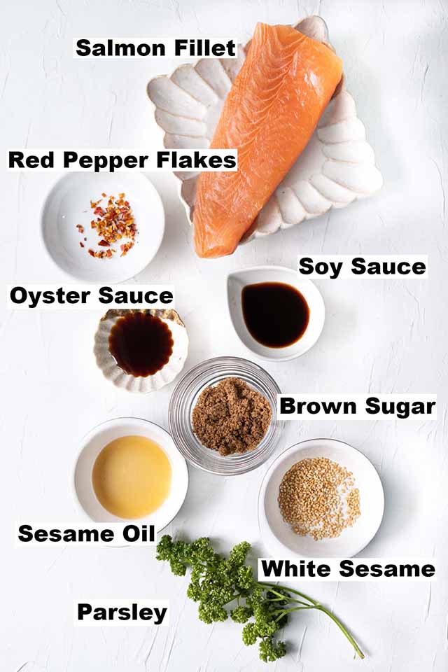 This image consists of ingredients such as salmon filet, red pepper flakes, soy sauce, oyster sauce, brown sugar, sesame oil, white sesame and parsley to make the Soy Glazed Salmon recipe.