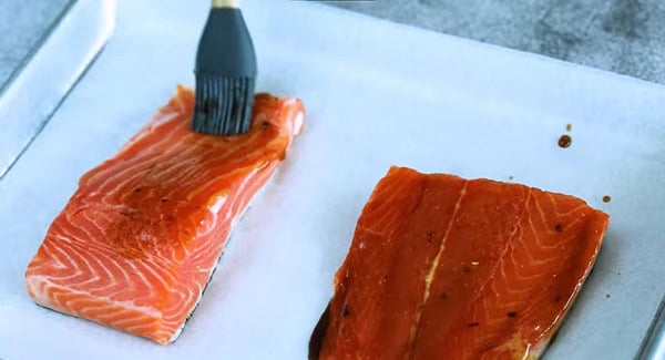 Brushing soy glaze into salmon fillets.