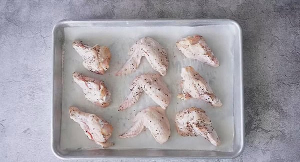 Seasoned chicken wings in a baking sheet.