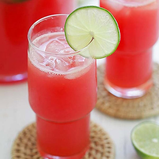 Watermelon-lime agua fresca served with ice in a tall glass with a slice of lime. 