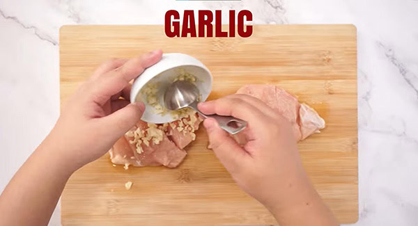 Minced garlic is added on the chicken breasts. 
