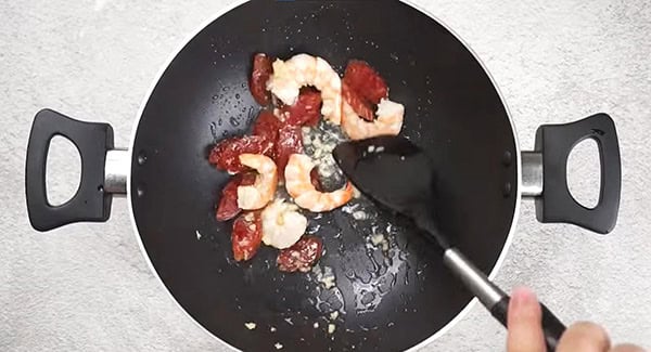 Shrimp, Chinese sausage and garlic being stir fried in a wok. 
