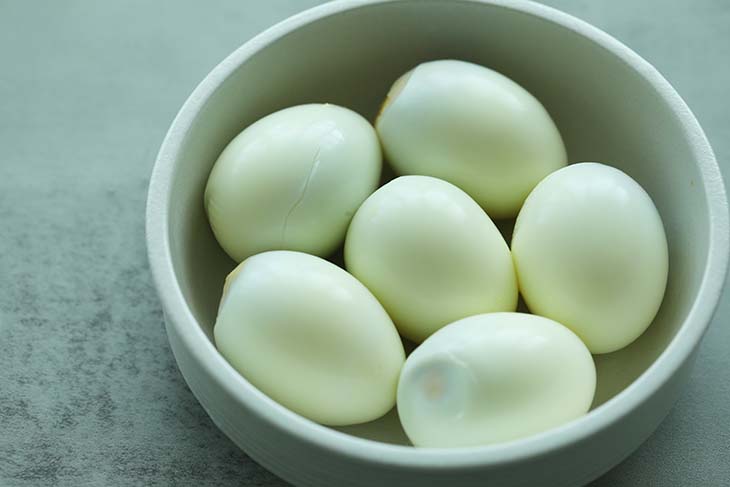 Peeled hard boiled eggs in a bowl.