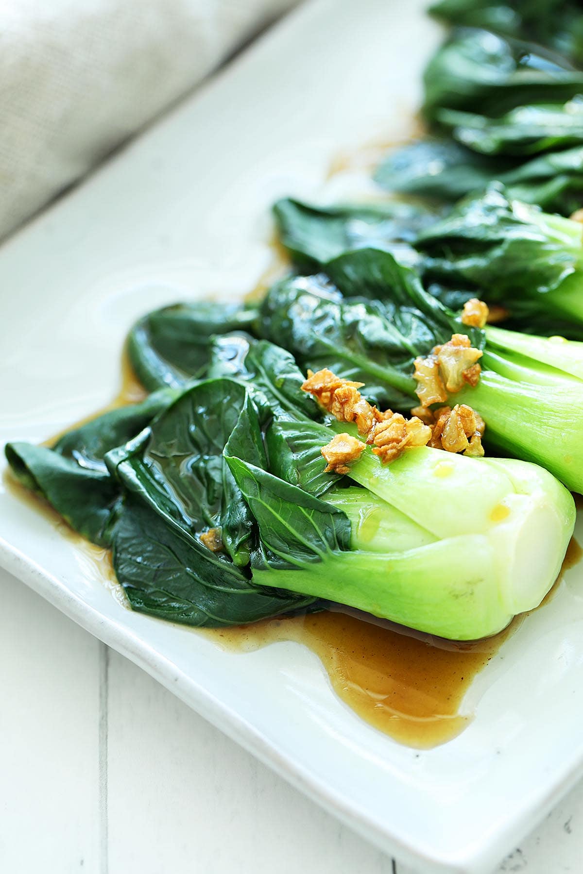 A small baby bok choy with oyster sauce and garlic on a plate. 