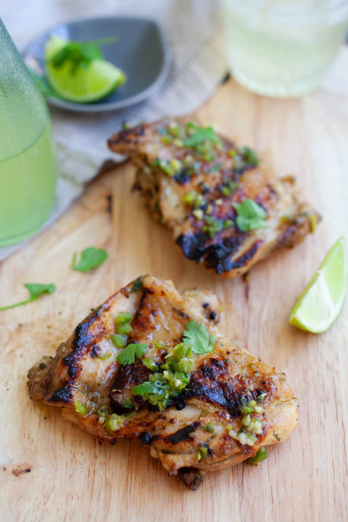 Two pieces of chicken thighs with cilantro and lime wedges, ready to serve. 