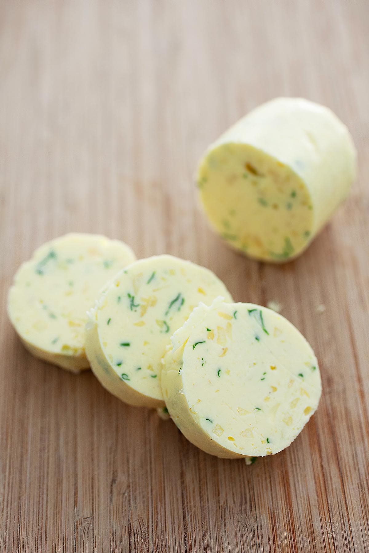 Cylindrical homemade garlic butter sliced in round pads.