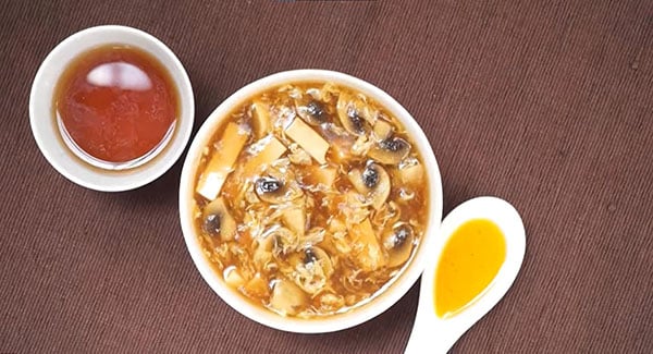 Hot and sour soup served with a side of soy sauce.