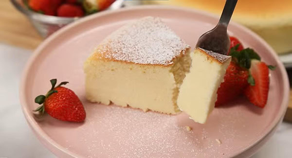 Japanese cheesecake dusted with powdered sugar and served on a plate with strawberries. 
