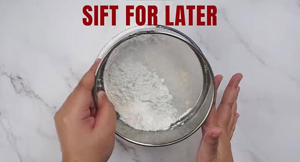 Cake flour and corn starch being sifted into a bowl. 