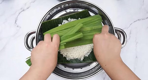 Banana leaf, glutinous rice and pandan leaves in a steamer. 