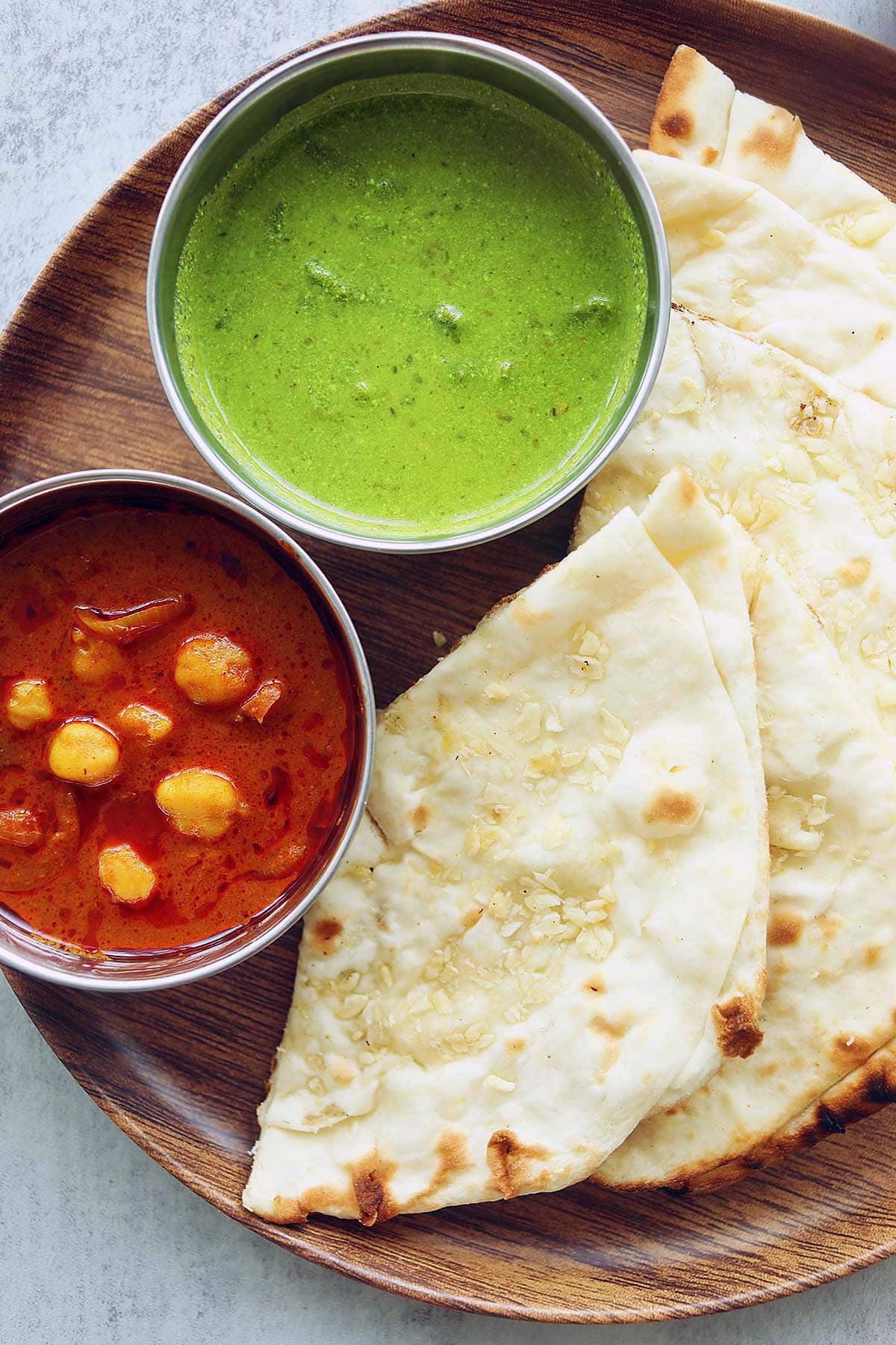 Naan served with mint chutney dip and chana masala on a tray.  