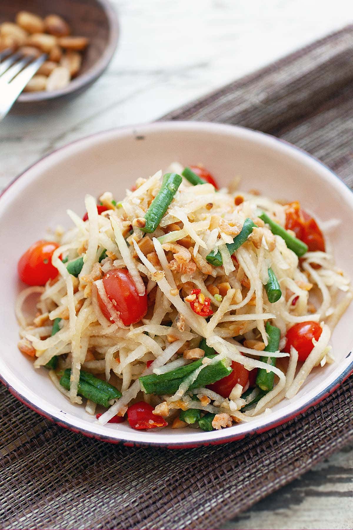 Som Tum or Som Tam Thai papaya salad made with green beans and tomatoes. 