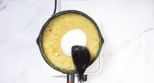 Blended pineapples, sugar and cloves in a deep pan stirred using a spatula. 
