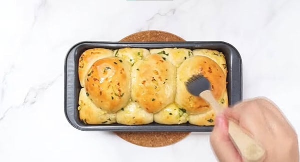 Butter mixture is basted on the pull apart garlic bread.