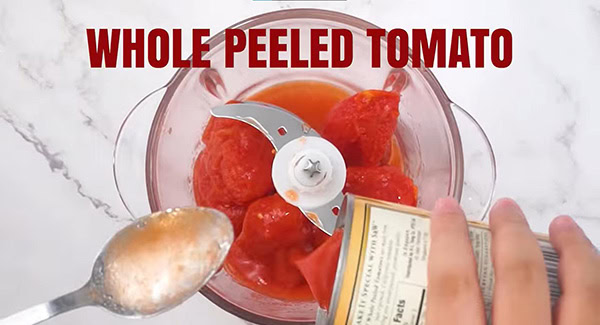 A can of whole peeled tomatoes in a food processor. 