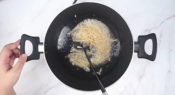 Ginger strips being stir fried in a wok using a spatula. 