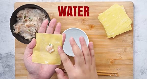 Add the filling to the middle of the wrapper. Dip your index finger into some water and trace it along the outer edges of the wrapper.