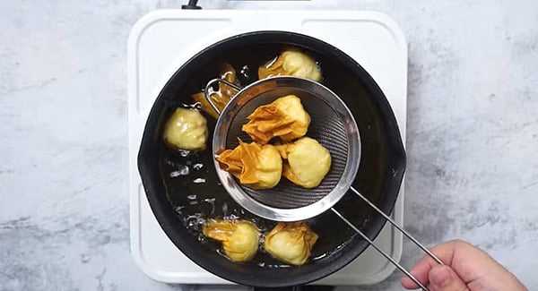 Deep fry the wontons until golden brown, then remove them using a strainer.