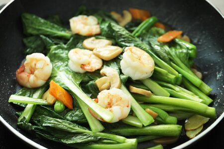 Cooking fresh you choy sum in a wok. 
