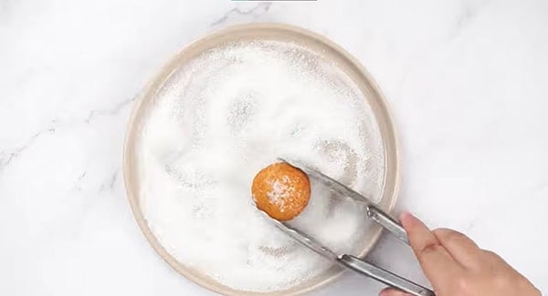 Roll the warm doughnut holes in sugar. 