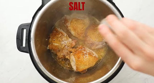 Salt being added to the pot with the brown sugar garlic sauce chicken thighs. 