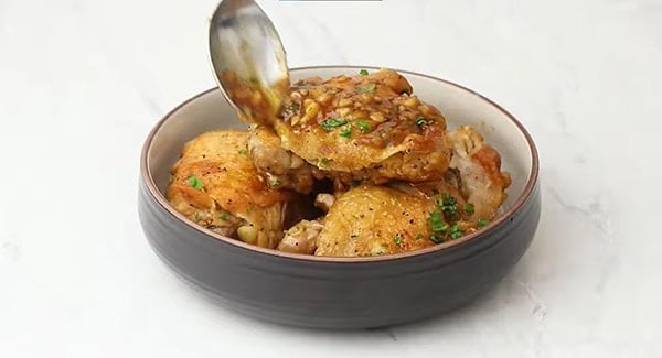 Instant pot brown sugar garlic chicken thighs served with parsley and drizzled additional brown sugar garlic sauce.