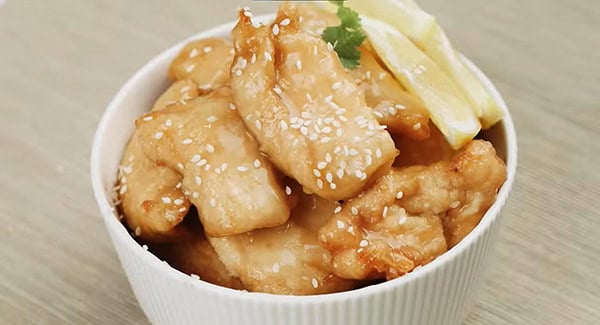 Lemon chicken with white sesame seeds in a bowl. 