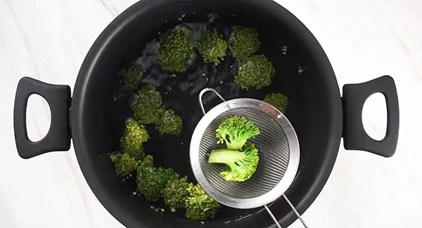 Broccoli florets being cooked in a pot of water. 