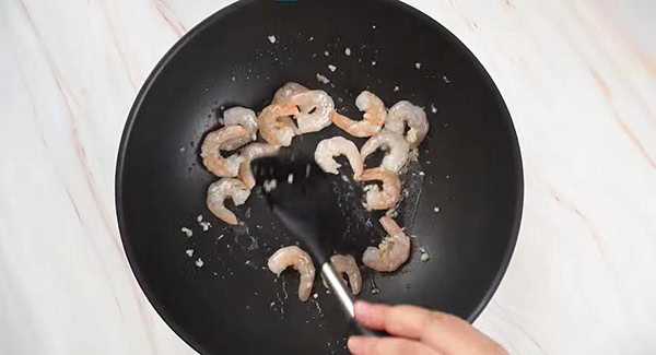 Shrimp being stir fried in a pan. 