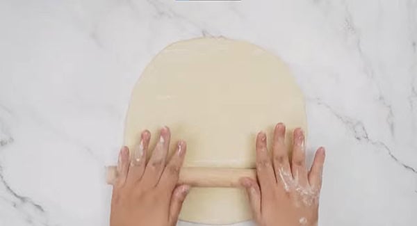 Dough being rolled out into a rectangular shape. 