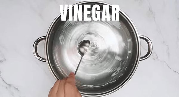 Vinegar is being poured into the bottom of steamer with water. 