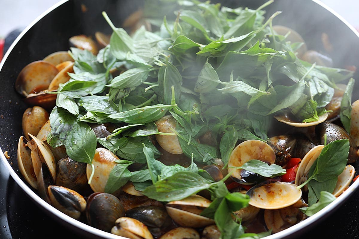 Thai basil leaves with clams in a skillet. 