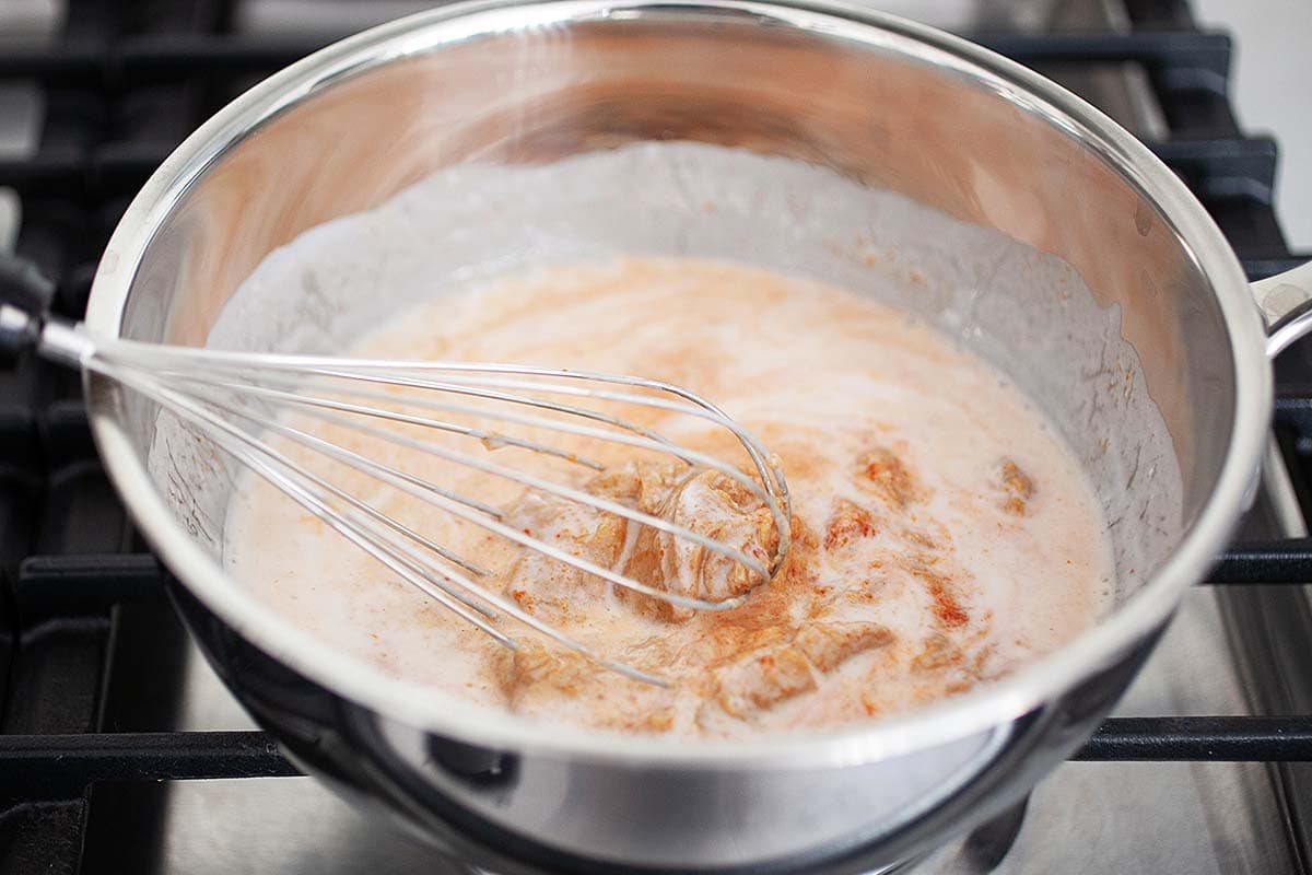 Whisking spicy Thai peanut sauce ingredients  in a sauce pan. 