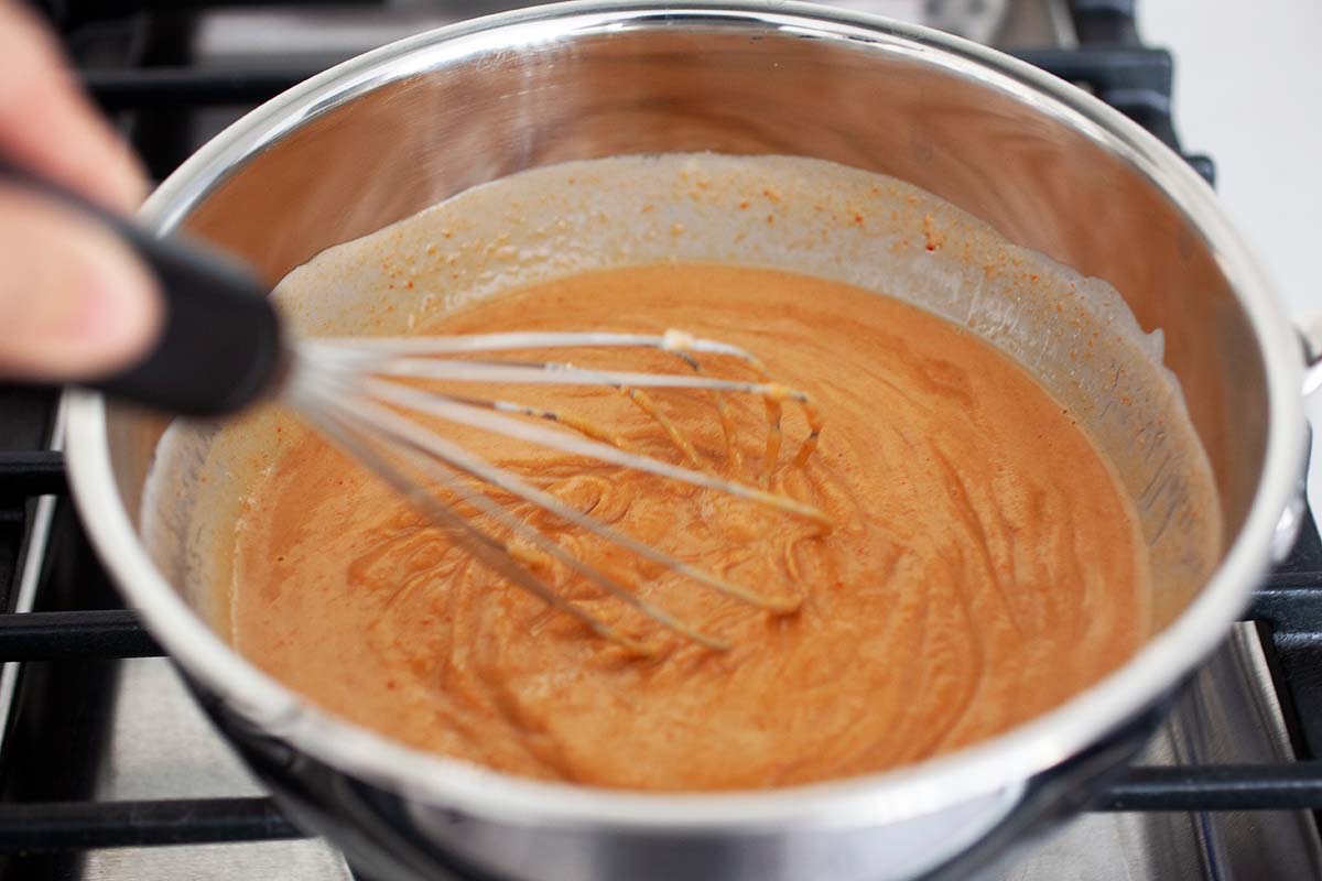 Peanut butter thai sauce bubbling in a saucepan.