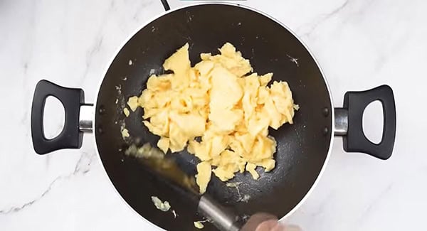 Scramble the eggs in a wok using a spatula. 